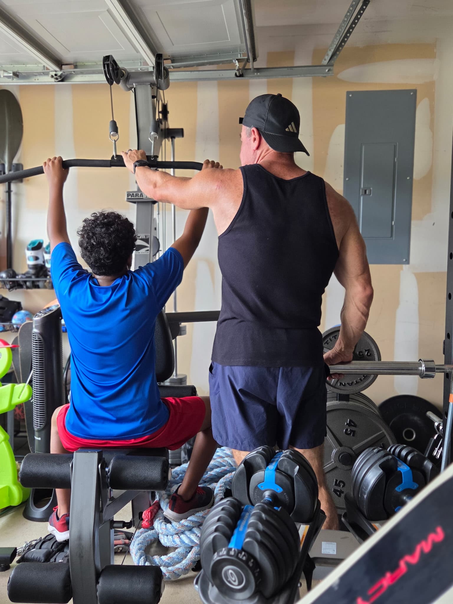 Jeff Mensing spotting a young client through a lat pulldown in his garage gym