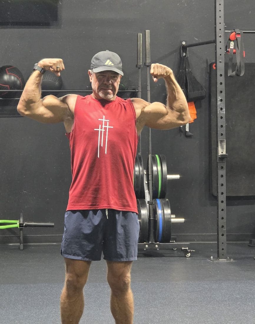 Jeff Mensing, founder of Refinery Fitness, flexing in a training gym in Buda, Texas
